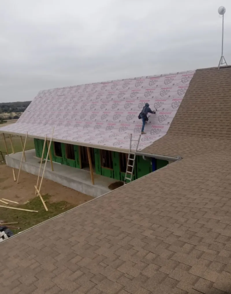 Worker preparing underlayment for a metal roof installation in Herrin